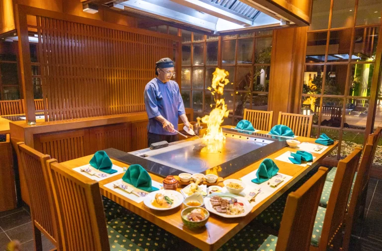 A chef prepares food on a grill in a genji japanese restaurant, highlighting the art of cooking in a bustling culinary environment.