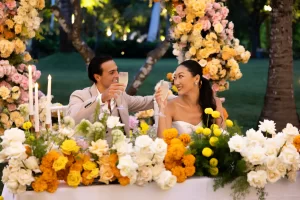 A bride and groom toast with champagne flutes at their wedding reception in Nusa Dua, Bali, surrounded by festive decorations.