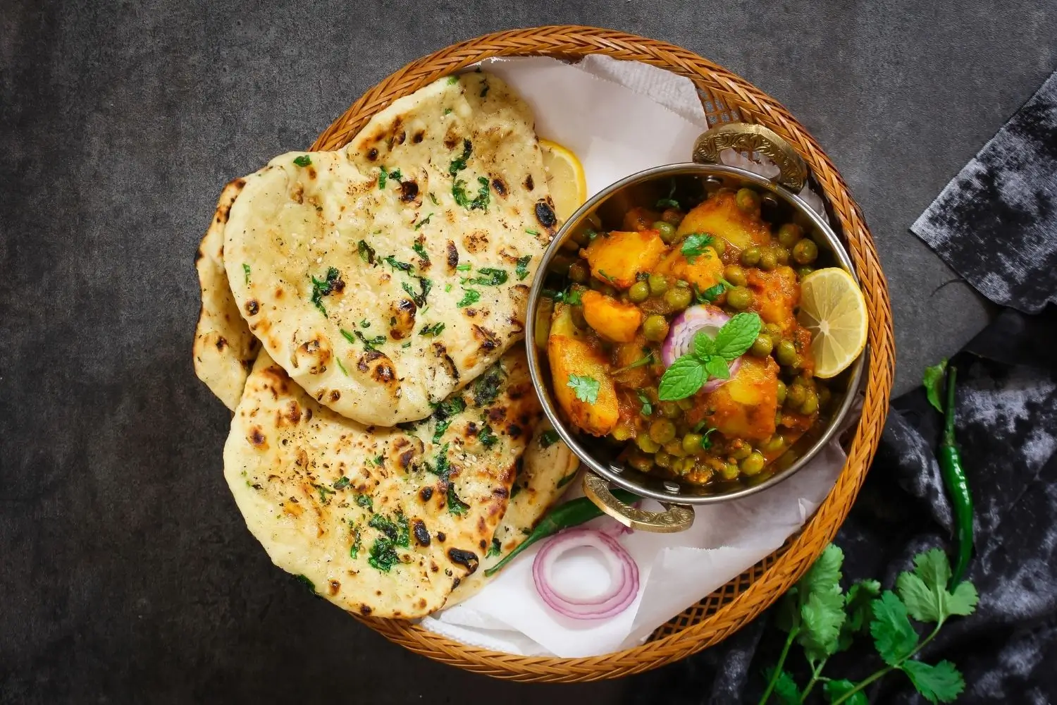 A plate of Indian food featuring Butter Naan alongside a colorful assortment of vegetables.