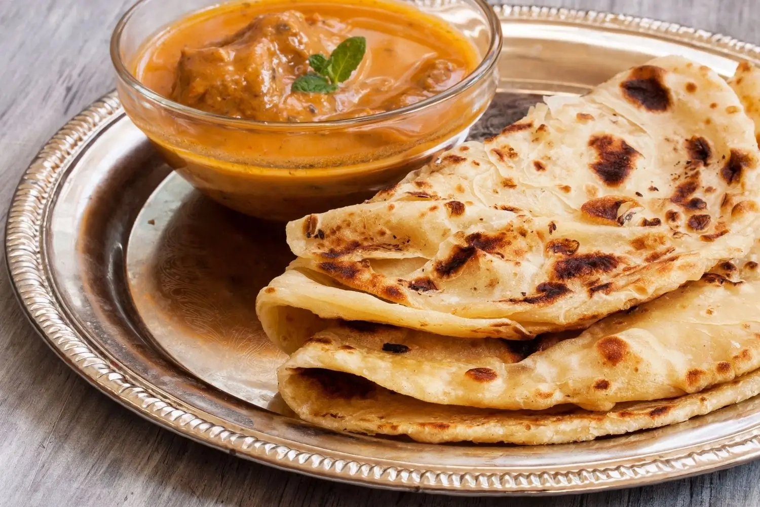 Indian flatbreads served with curry sauce on a silver plate, showcasing a traditional Chapati Set.