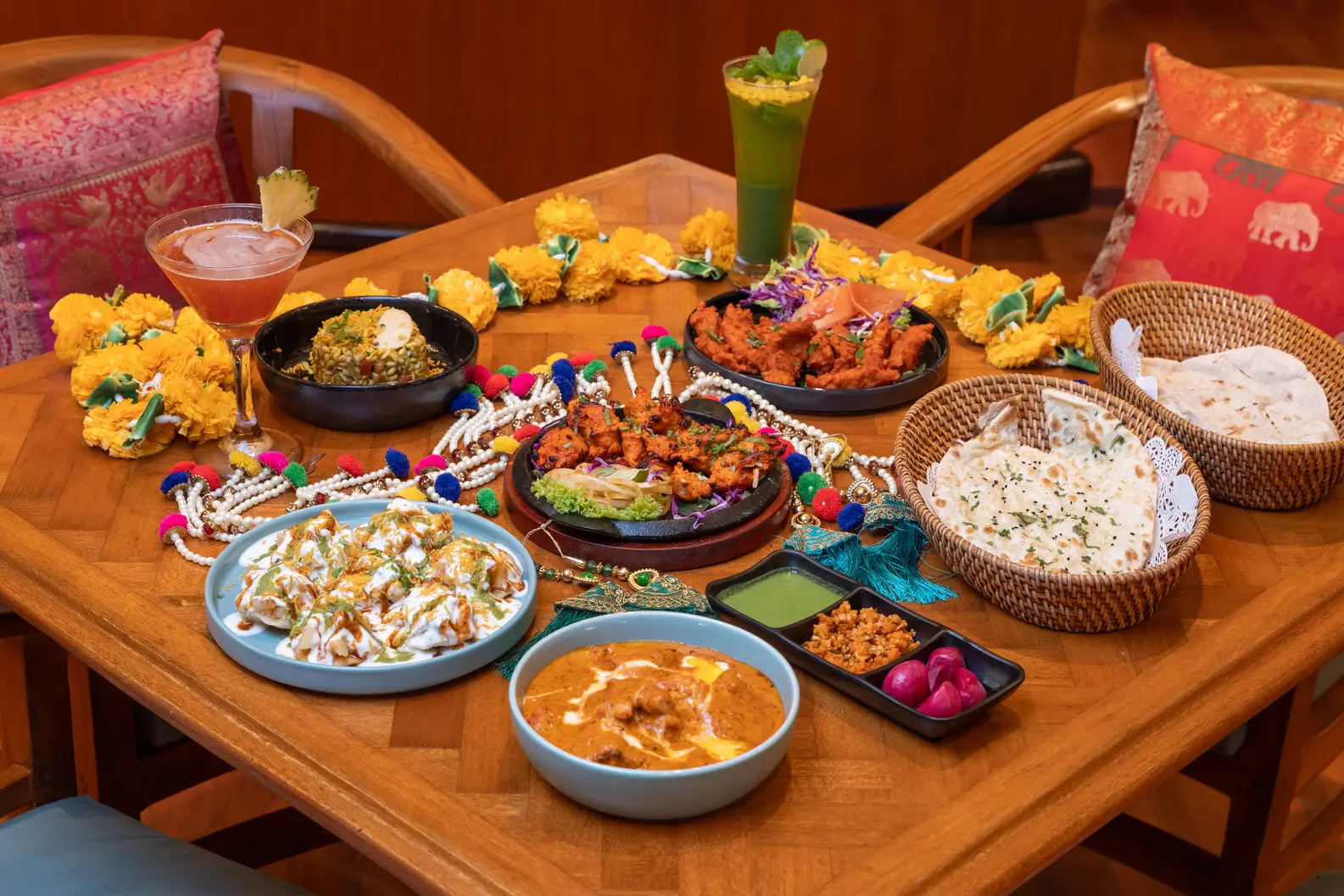 A richly set table brimming with different indian food items, including appetizers, main courses, and desserts in vibrant colors at the Ganesha Ek Sanskriti, indian restaurant in nusa dua
