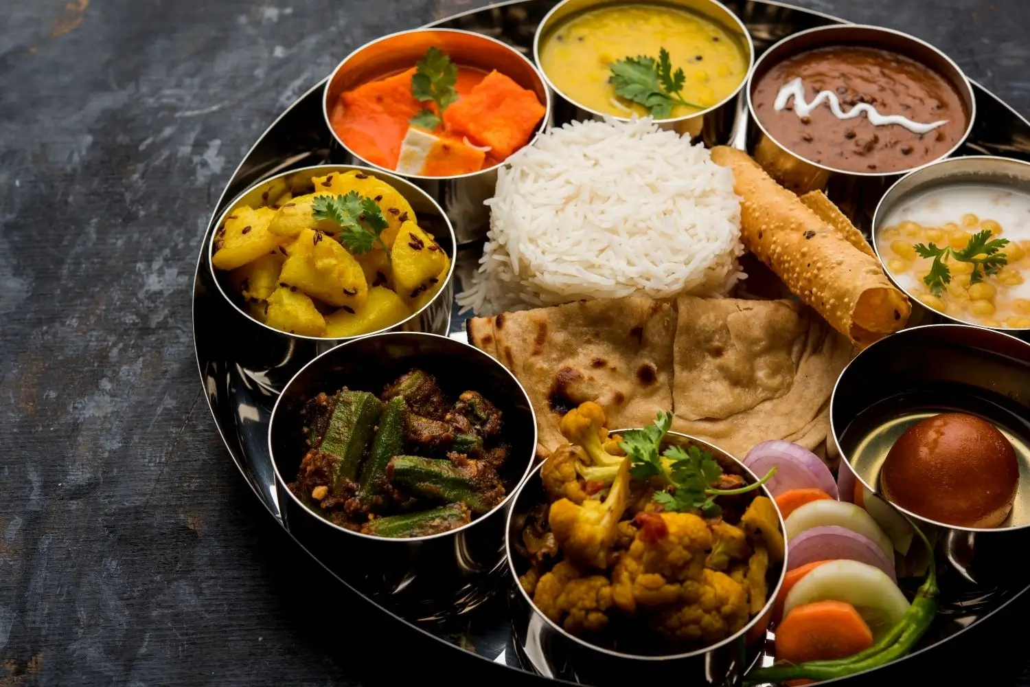 A Royal Thali displaying a variety of Indian dishes, elegantly presented on a round plate.