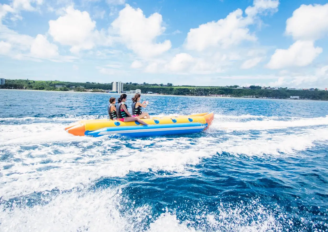 A group of people enjoying a fun ride on a bright yellow banana boat, one of the most popular Nusa Dua watersport activities, out on the sparkling blue water.
